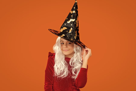 Happy Halloween. Girl witch in Halloween costume isolated on orange. Trick or treat. All Hallows...