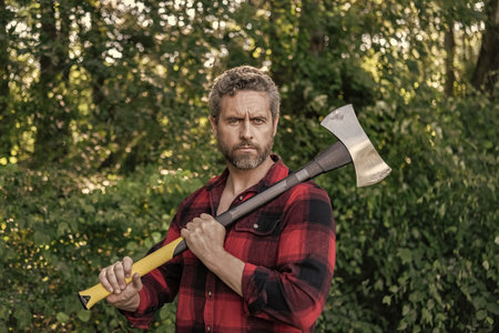 Lumberjack with axe. Masculinity. Hispanic lumberjack man with axe. Lumberjack axe. Man with logging axe. Hardworking man. Lumberjack hardworking outdoor. Man hold rusty axeの写真素材