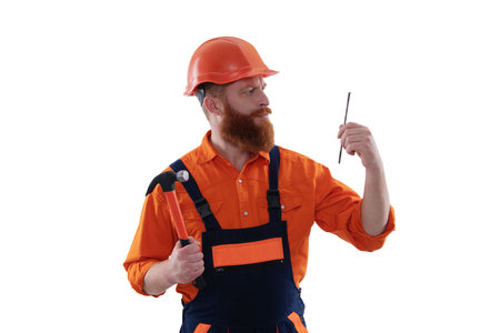 Repairman in uniform has hammer. Bearded repairman with hammer. Carpenter repairing with nail...