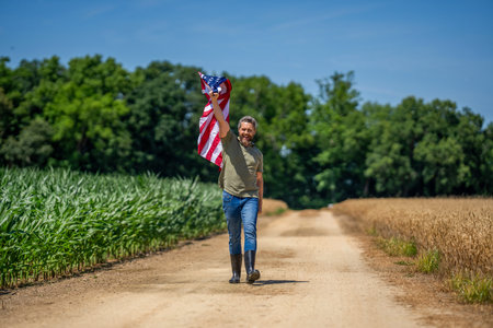 Man in field. Man with American flag in crop field. Independence day of America. 4th of July. Memorial day. American labor day. American flag and man farmer. Flag of USA. Independence dayの写真素材