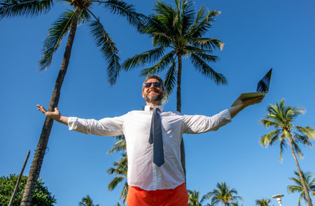 Businessman on summer. Online freelance work. Successful businessman worker with laptop. Business man using laptop among palm tree. Business trip success. Man freelance worker onlineの写真素材