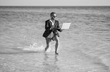 successful businessman has business success run with laptop in sea at summer vacation