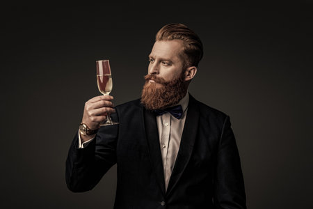 Cheers. Bearded man with formal look. Celebrate with champagne. Cheering and celebrating. Elegant tuxedo man hold glass of champagne isolated on black. Celebrating success. Champagne receptionの写真素材