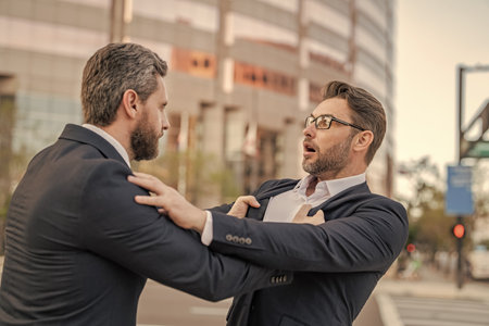 Two businessmen conflicting at fight outdoor. Businessmen having conflict in business. Conflict between boss and employee. Fight aggression. Angry businessmen threatening. Business conflictの写真素材