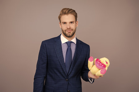 Businessman in suit hold valentines day present toy at corporate event isolated on greyの写真素材