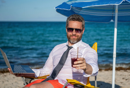 Online freelance. Businessman remote worker with laptop. Business man using laptop in beach. Travel and business. Man freelance work online at sea beach. Businessman on summer vacation. Sea lifestyleの写真素材