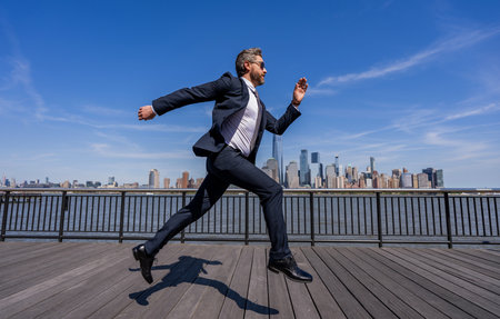 Business success in big city. Businessman running to success. Business success. Successful businessman hurrying on New York city skyline. Business man in Manhattan. Run and late businesの写真素材