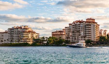 Motor boat yacht floating to marina. Luxury yacht boat at Fisher island. Summer vacation. Fisher island residential building and luxury yacht boat. Panorama view of Fisher island, Miamiの写真素材