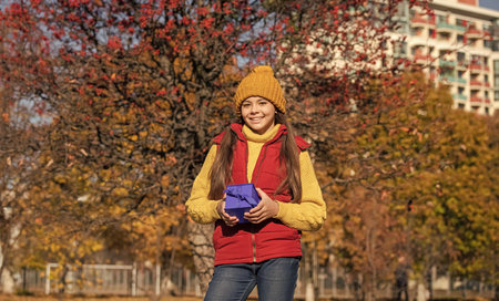 teen girl smile with present box in autumnの写真素材