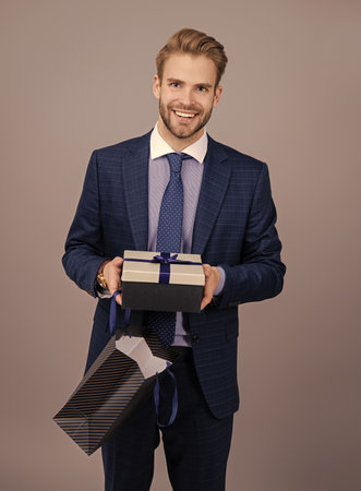 Successful boss hold gift. Anniversary. Businessman rewarded for good work. Secret valentine at business corporate. Business man with corporate gift isolated on grey. Corporate present. Mens dayの写真素材