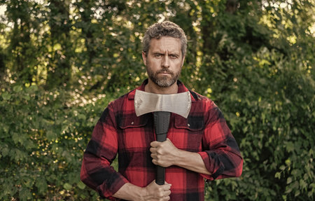 Lumberjack axe. Man with logging axe. Hardworking brutal man. Lumberjack hardworking outdoor. Brutal lumberjack. Brutality and masculinity. Hispanic lumberjack man with axe. Strong woodcutterの写真素材