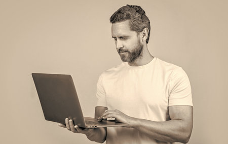 photo of cheerful man blogger with laptop. man blogger isolated on yellow. man bloggerの写真素材