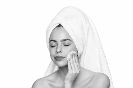 Woman use cotton pad. Skincare. Remove the makeup. Beauty routine. Woman in towel cleaning face skin. Cleansing skin with cotton ball. Skincare cosmetology. Beauty day in spa. Brightening serumの写真素材