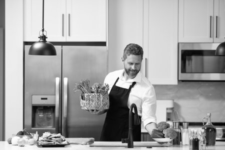 Home menu. Man cooking in kitchen. Healthy food for dinner. Man cooking home food. Healthy food, cooking concept. Mature man in apron choose ingredientの写真素材