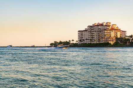 Vacation on summer. Fisher island building. Luxury motor boat yacht. Yacht go to marina. Boating and yachting. Luxury life. Yacht at Fisher island luxury residential buildingの写真素材