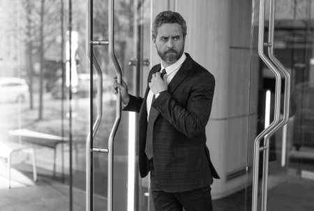 Boss man leaving business office. Business man. Successful businessman entering office. Adult entrepreneur at office door. Hispanic businessman in suit leaving office building. Global businessの写真素材