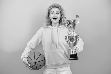 Woman with basketball ball and champion cup. Happy girl basketball player. Sport success. Woman won the prize. Celebrating success. Winning the game. Sport achievement award. Inspirational championの写真素材