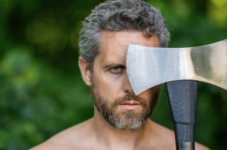 Lumberjack outdoor portrait. Hispanic lumberjack man face with axe. Lumberjack axe. Man with logging...