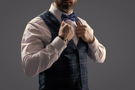 Gentleman in tuxedo vest. Businessman at formal event. Groom has tuxedo style. Tux of gentleman. Tux suit, cropped. Man with bow tie isolated on grey. Stylish man in elegant black suit. Businessmanの写真素材