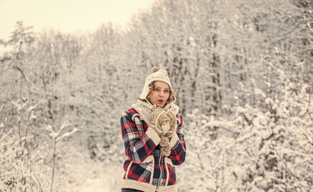 Favorite season. Enjoy every snowflake. Winter outfit. Woman wear warm accessories stand in snowy nature. Cheerful emotional girl having fun outdoors.の写真素材