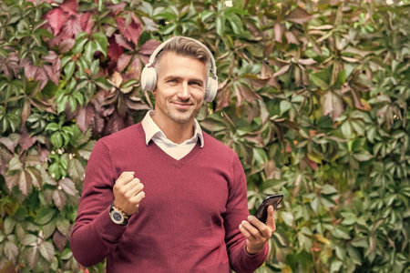 Mature man enjoy listening music in headphones outdoor. Autumn music playlist. Man listening music...