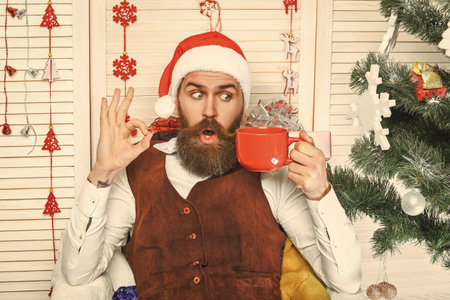 Delicious cocoa for Christmas. Man celebrate Xmas. Merry Christmas. Santa Claus retro man drinking coffee. Xmas holiday celebration. Santa man in retro style with mug.の写真素材