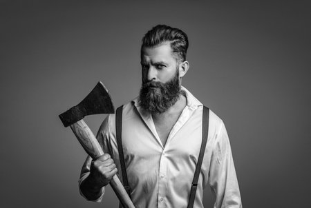 Brutal bearded man in vintage suspenders holding ax isolated on greyの写真素材