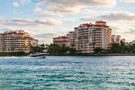 Luxury motor boat yacht. Yacht go to marina. Boating and yachting. Luxury lifestyle. Yacht at Fisher island luxury residential building. Vacation on summer. Fisher island building. Sea vacationの写真素材