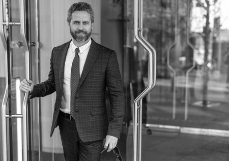Successful businessman entering office. Mature entrepreneur at office door. American businessman in...