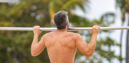 Man muscular back athlete doing pull up in outdoor gym. Sport lifestyle. Muscular biceps and...