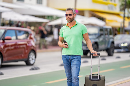 Traveler suitcase for summer trip. Man booking summer trip. Hispanic tourist traveler book online outdoor. Tourist with travel bag. Traveler using phone. Tourist booking vacation trip. Buy ticketの写真素材
