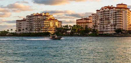 Yacht go to marina. Boating and yachting. Luxury lifestyle. Yacht at Fisher island luxury residential building. Vacation on summer. Fisher island building. Luxury motor boat yacht. Touristic spotの写真素材