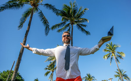 Business man using laptop near palm tree. Business trip. Man freelance work online at beach. Businessman on summer vacation. Online freelance work. Businessman boss with laptop. Outdoor officeの写真素材