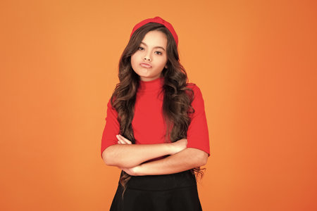 Girl face portrait. Hair style. Funny girl isolated on orange. Teen girl portrait with curly hair. Teen style. Stylish model. Stylish girl with long curly hair. Funny faceの写真素材