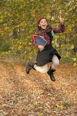 Girl jump in autumn hold school homework. Back to school. Teen girl with homework jump in autumn park. School education of girl outdoor. Knowledge and education. Knowledge dayの写真素材