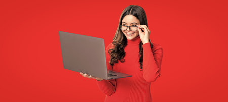 Teen girl with laptop isolated on red. Teen girl study online. Online education. Back to school. Knowledge and online education. Video lesson on laptop. Online coursesの写真素材