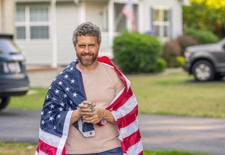 Value added tax. Taxation system. Patriotic man. Man with American flag and dollar money. Inflation concept. American tax policy. Hispanic man and USA flag. Paying tax in America. Copy space bannerの写真素材