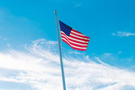National waving flag of united states on blue sky. Independence day. Patriotic symbol. American Flag for Memorial Day or 4th of July. American flag waving in the wind. Flag of the USA. 4th of Julyの写真素材