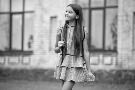 Happy teen school student girl with backpack standing outdoor at schoolyardの写真素材