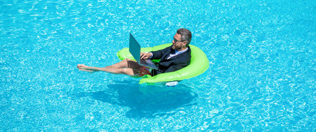 Businessman using laptop for freelancing in swimming pool. Business freelancing. Businessman on summer vacation. Business communication. Freelance man has online video call. Freelance working onlineの写真素材