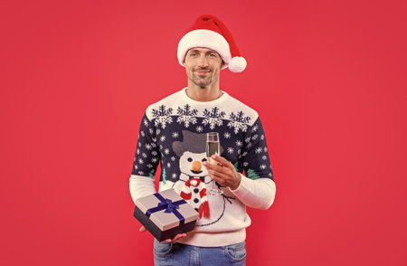 glad xmas man isolated on red background. man hold present for xmas in studio. xmas presentの写真素材