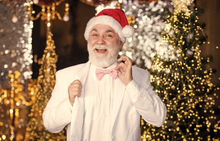 Family holiday. happy mature man white formal suit. businessman in event tuxedo. senior man santa christmas light illuminated background. bright and festive xmas mood. new year partyの写真素材