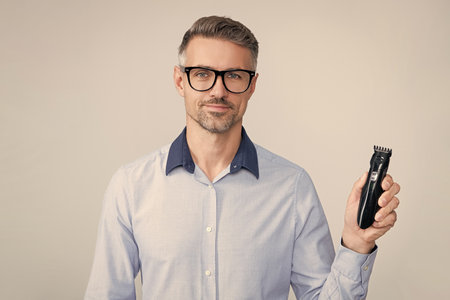 Man holding electric shaver. Mature man presenting electric razor. Haircare and shaving. Personal...