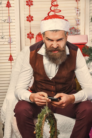 Bad Santa Claus bearded retro man with angry face in hat old Christmas wreath decoration for New...