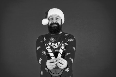 Merry Christmas. Happy New Year. Xmas holiday celebration. Santa Claus man at New Year eve. December holiday party for man in Santa hat. Xmas sweater. Christmas candy cane. Seasonal festivitiesの写真素材