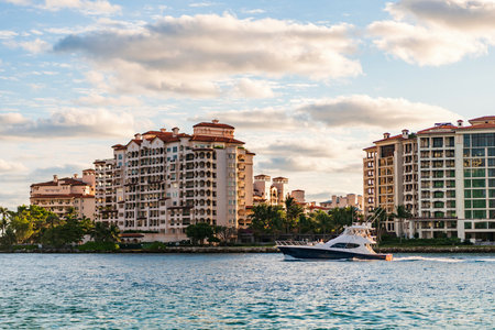 Motor boat yacht floating to marina. Luxury yacht boat at Fisher island. Summer vacation. Fisher island residential building and luxury yacht boat. Trip to Fisher island on yacht, Miamiの写真素材