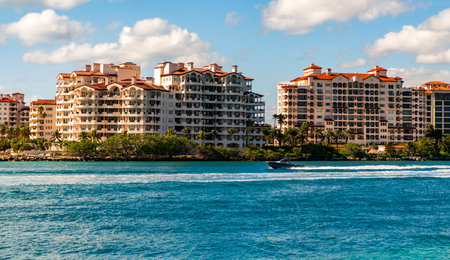 Vacation on summer. Fisher island building. Luxury motor boat yacht. Yacht go to marina. Boating and yachting. Luxury life. Yacht at Fisher island luxury residential buildingの写真素材