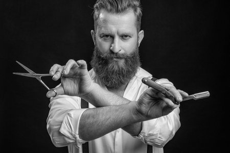 Hairdresser man. Professional barber man hold retro razor. Handsome hairstylist with haircut. Barbershop. Man hairdressing and barbering. Hairdresser at barbershop isolated on black. Retro fashionの写真素材