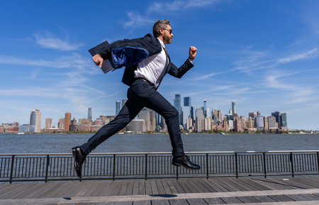 Successful businessman hurrying on New York city skyline. Business man in Manhattan. Business success in big city. Businessman running to success. Business success. Late meetingの写真素材