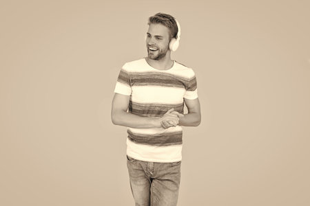 cheerful man listens to music on his headphones isolated on yellow background. man relaxes listen to...